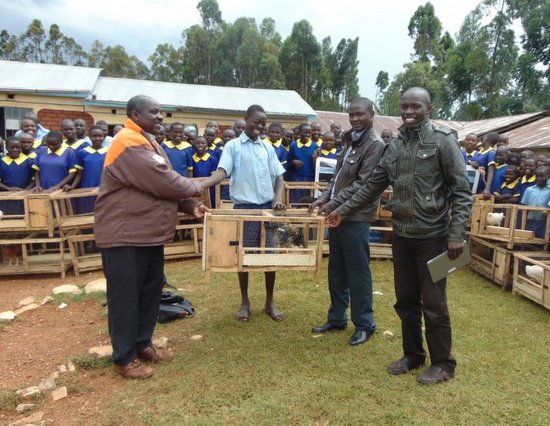 MakiniJames_One Hen Campaign Project Co-founders (in Leather Jackets) presenting a hen in a coop to pupil looking on is livestock officer from Kisii County Government